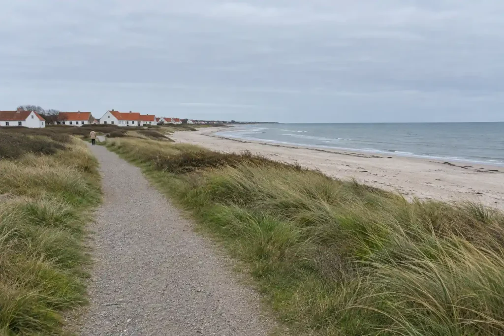 Skånsk kustmiljö som i wallander filmer, med grusstig, dyner och vita hus vid havet
